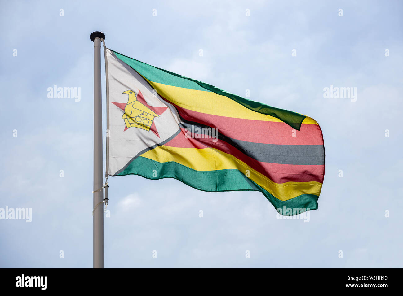 Zimbabwe flag, National symbol waving against clear blue sky, sunny day Stock Photo Alamy