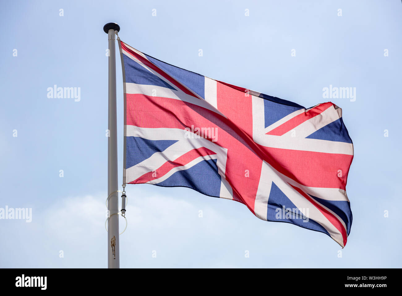 United Kingdom flag, Great Britain national symbol waving against clear blue sky, sunny day Stock Photo