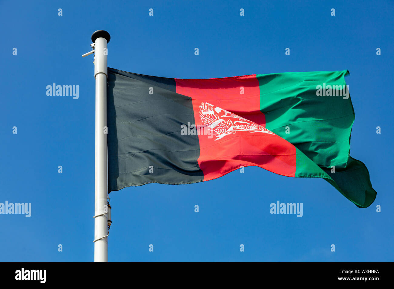 Afghanistan flag, national symbol waving against clear blue sky, sunny day Stock Photo
