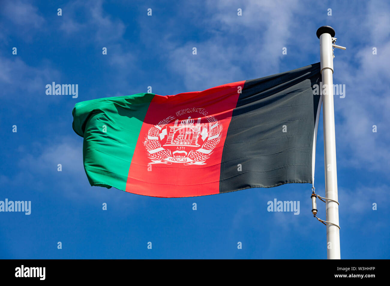 Afghanistan flag, national symbol waving against clear blue sky, sunny day Stock Photo