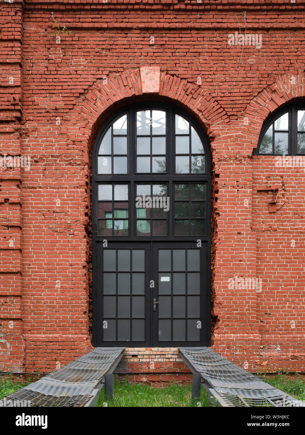 French arched window in an old red brick wall with metal rail rails ...