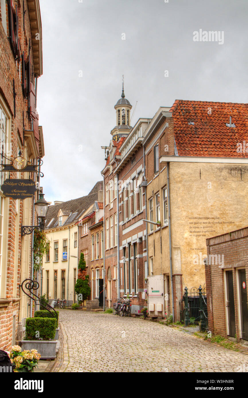Idyllic street with historic houses and cobblestone pavement, in the background a churchtower; the charming Dutch city of Zutphen Stock Photo