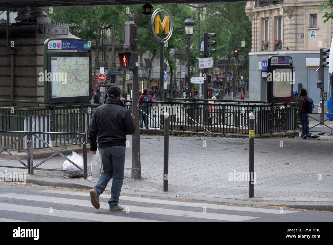 man crossing street under red traffic lights at metro station Barbes Rochechouart, Paris, France Stock Photo
