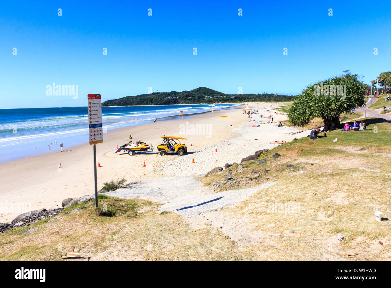 Byron Bay, Australia - 14th May 2015: People sitting on grass and the beach. The area is popular with young people. Stock Photo