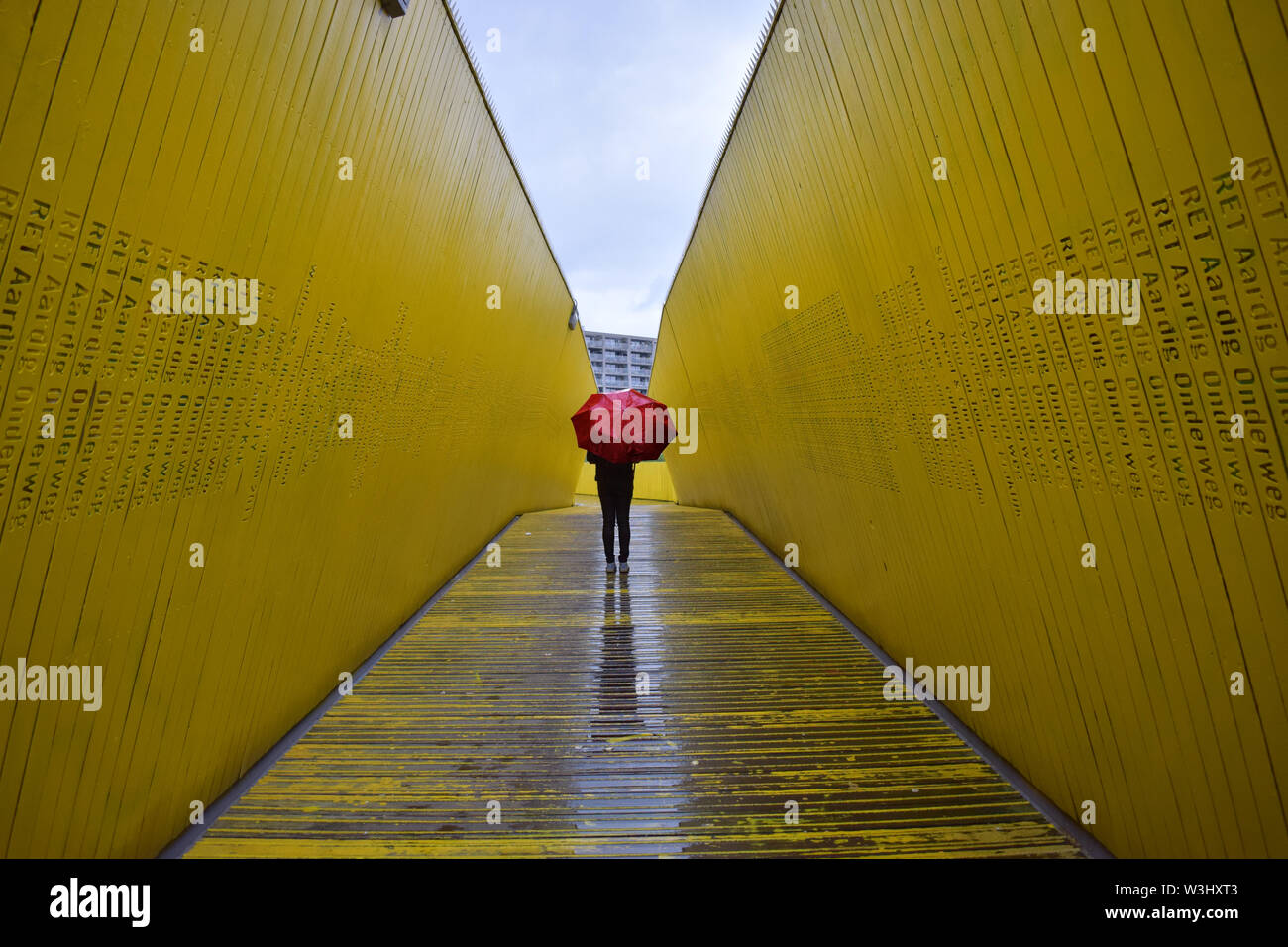 A girl standing alone in rain with a red umbrella Stock Photo