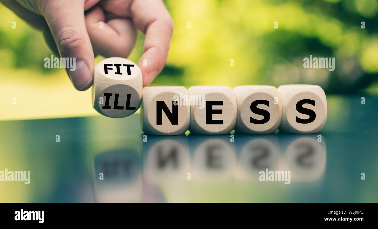 Hand turns a cube and changes the word 'illness' to 'fitness'. Stock Photo