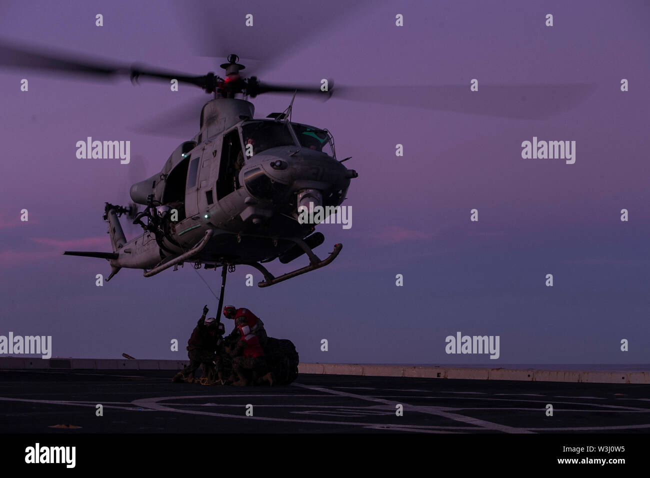 Marines with the 31st Marine Expeditionary Unit attach cargo to a UH-1Y Huey helicopter with Marine Medium Tiltrotor Squadron 265 during a landing support exercise aboard the amphibious transport dock USS Green Bay (LPD 20), underway in the Coral Sea, July 12, 2019. Green Bay, part of the Wasp Amphibious Ready Group, with embarked 31st MEU, is currently participating in Talisman Sabre 2019 off the coast of Northern Australia.  A bilateral, biennial event, Talisman Sabre is designed to improve U.S. and Australian combat training, readiness and interoperability through realistic, relevant traini Stock Photo
