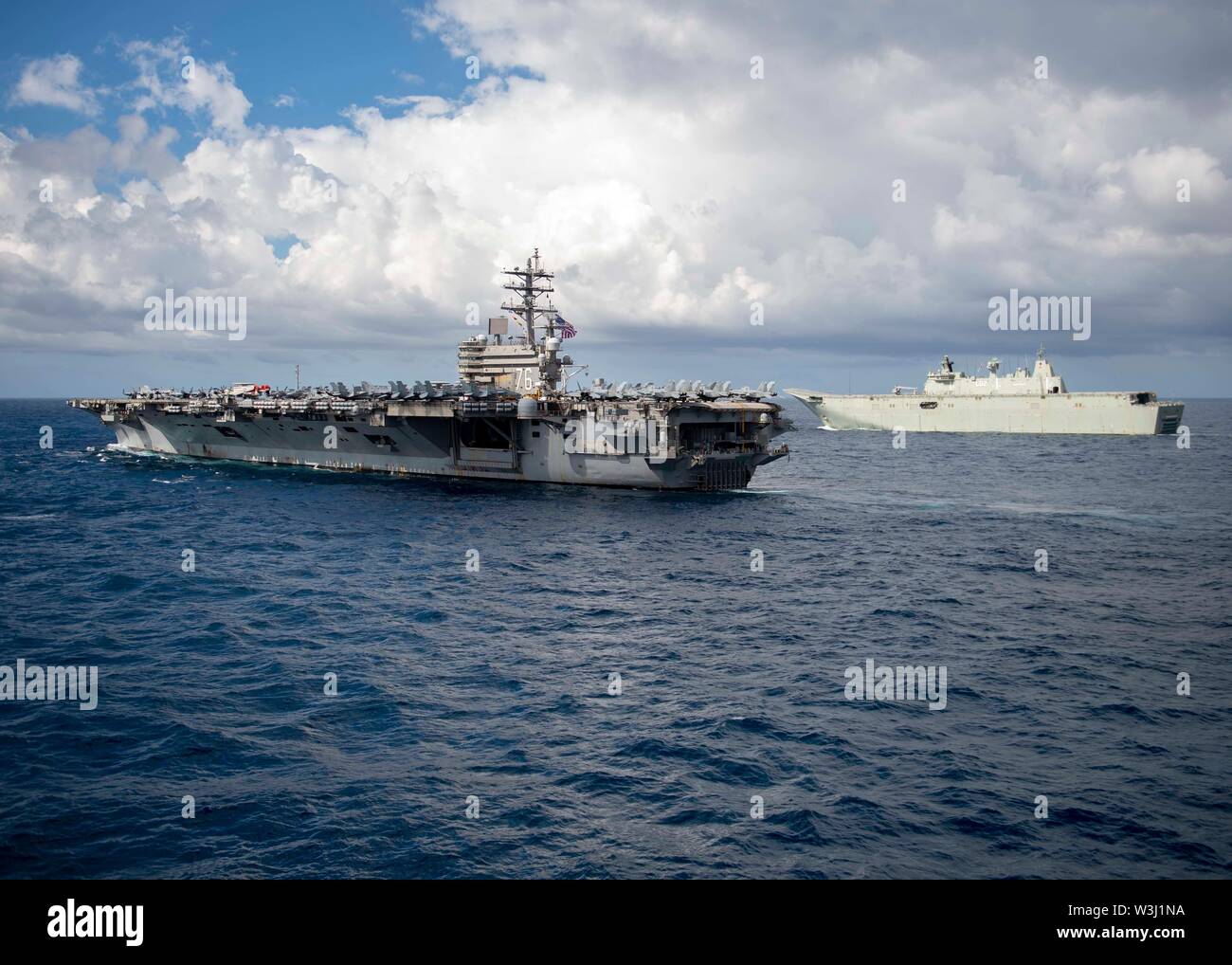 190711-N-WK982-3060 CORAL SEA (July 11, 2019) The U.S. Navy Nimitz-class aircraft carrier USS Ronald Reagan (CVN 76), left, and the Royal Australian Navy Canberra-class landing helicopter dock ship HMAS Canberra (L02) maneuver into formation during Talisman Sabre 2019. Talisman Sabre 2019 illustrates the closeness of the Australian and U.S. alliance and the strength of the military-to-military relationship. This is the eighth iteration of this exercise. (U.S. Navy photo by Mass Communication Specialist 2nd Class John Harris/Released) Stock Photo