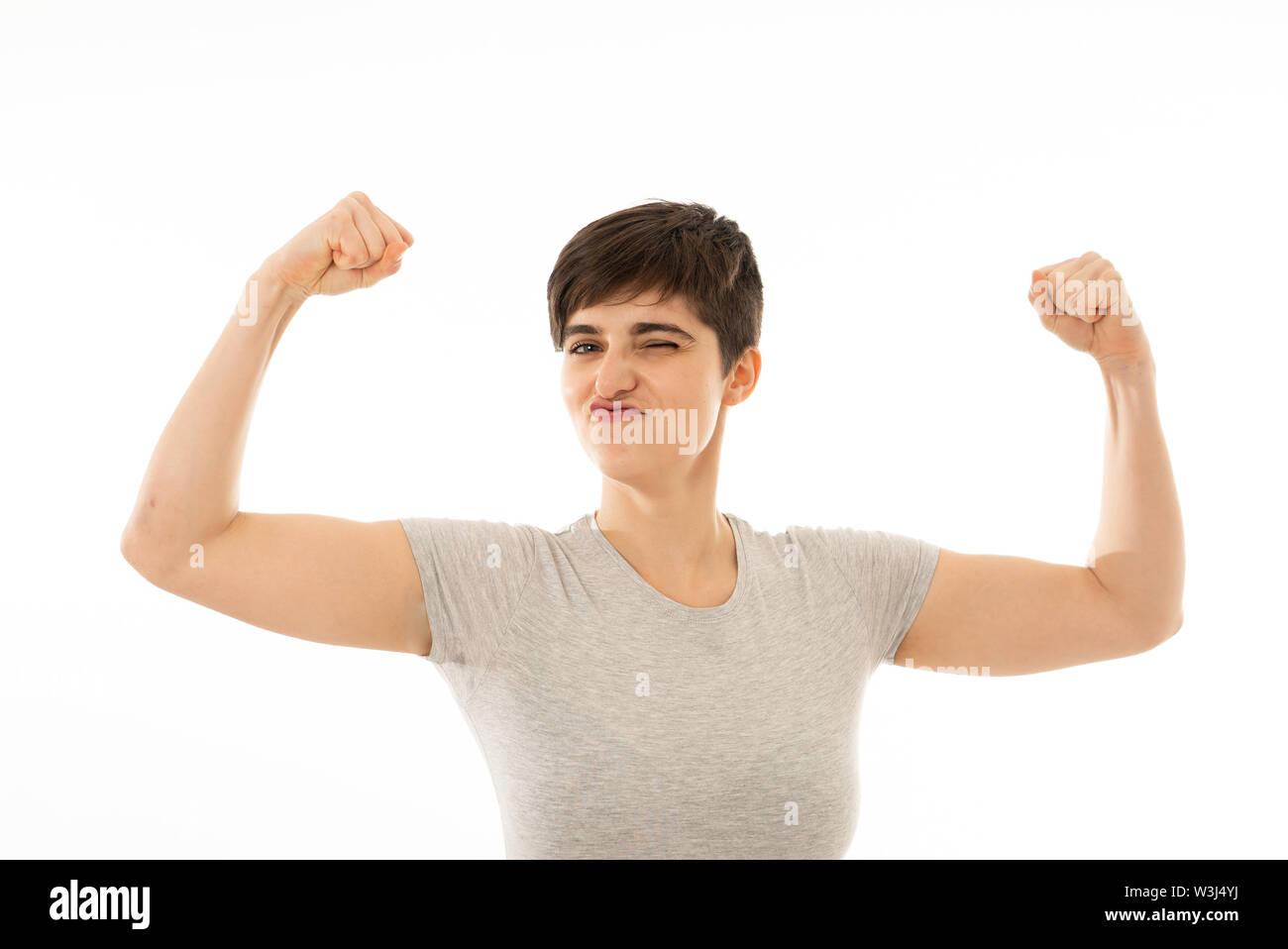 Portrait of young strong beautiful and funny caucasian woman showing arms muscles smiling proud having fun. In people, Happiness, Fitness, success Hum Stock Photo