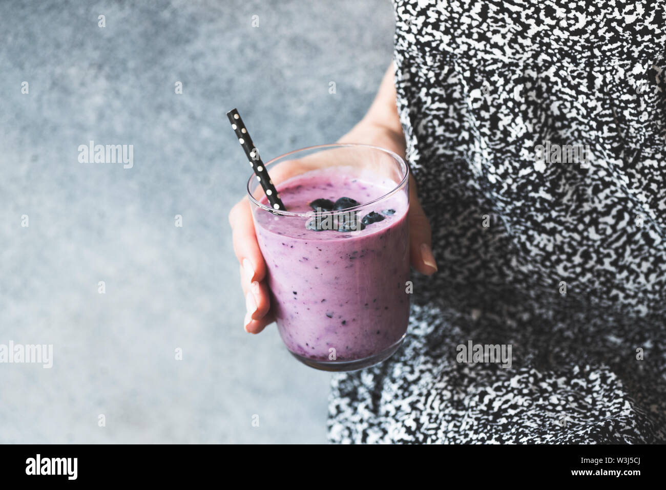 Glass of blueberry smoothie in woman's hand. Clean eating, dieting, detox and weight loss concept Stock Photo