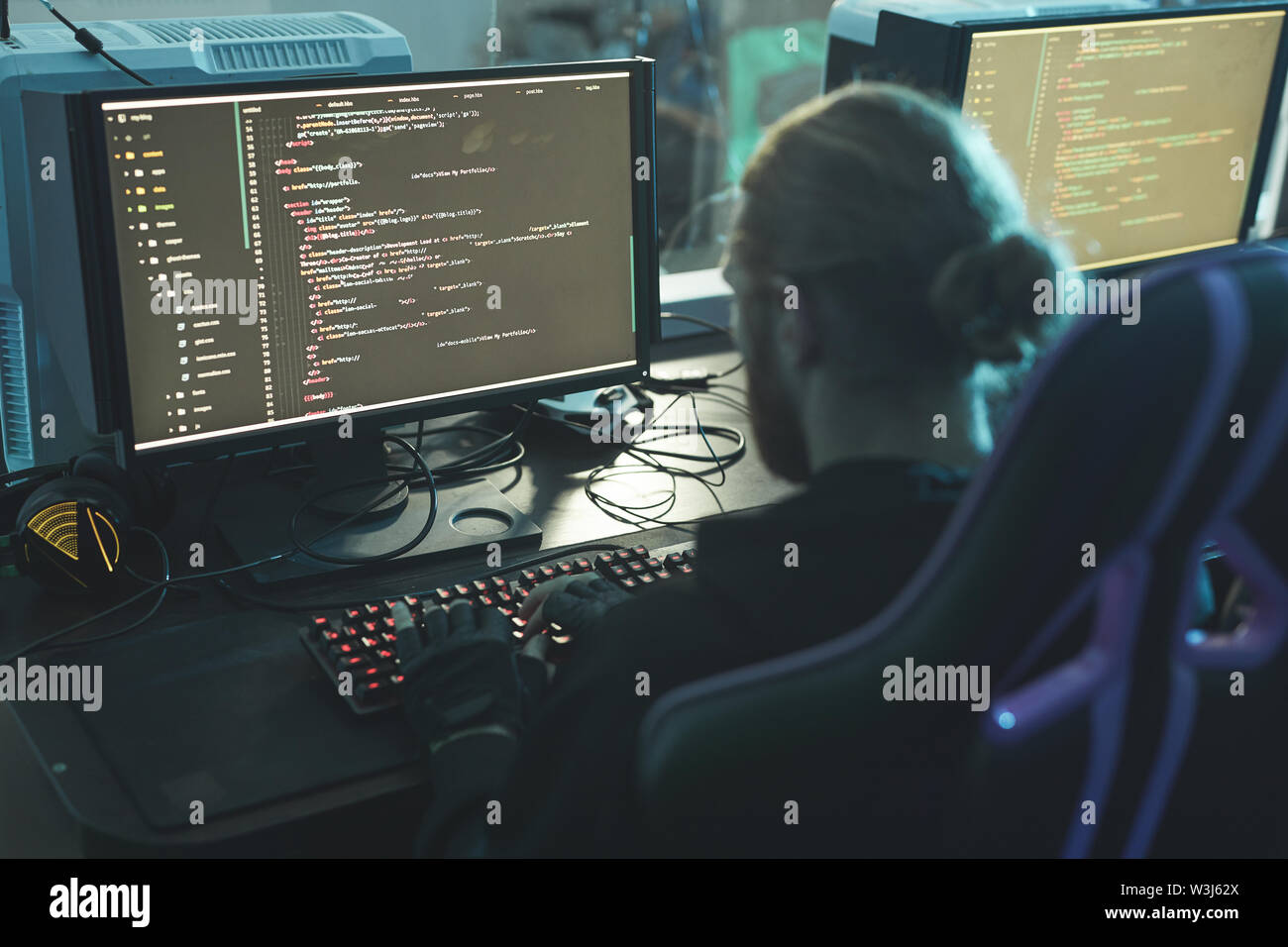 Rear view of concentrated software engineer sitting at table and composing app script while working in programming company Stock Photo
