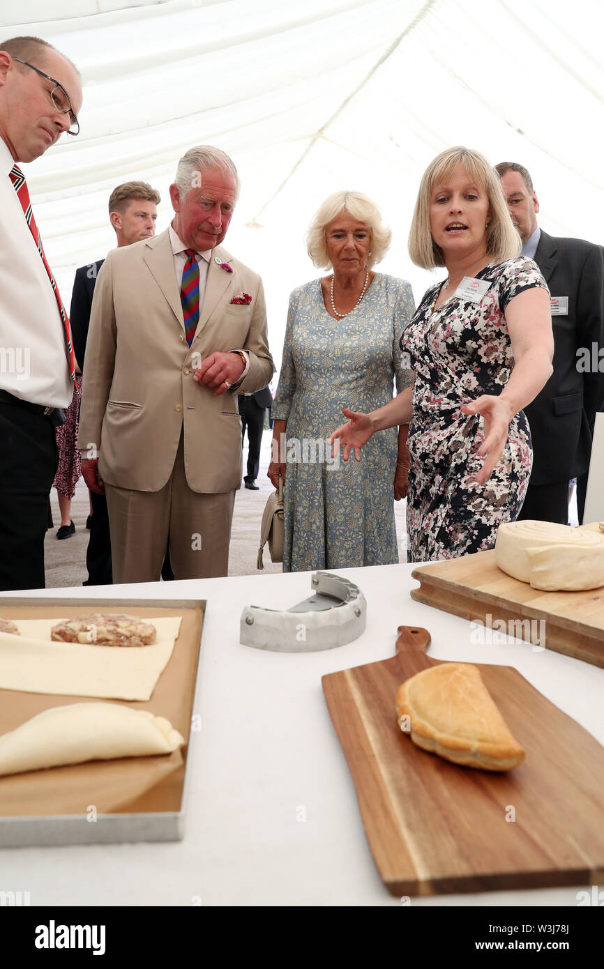 Production Director At Ginsters Julie Roberts Shows The Prince Of Wales And The Duchess Of Cornwall Some Of Their Products During A Garden Party To Celebrate The 50th Anniversary Of Ginsters Bakery
