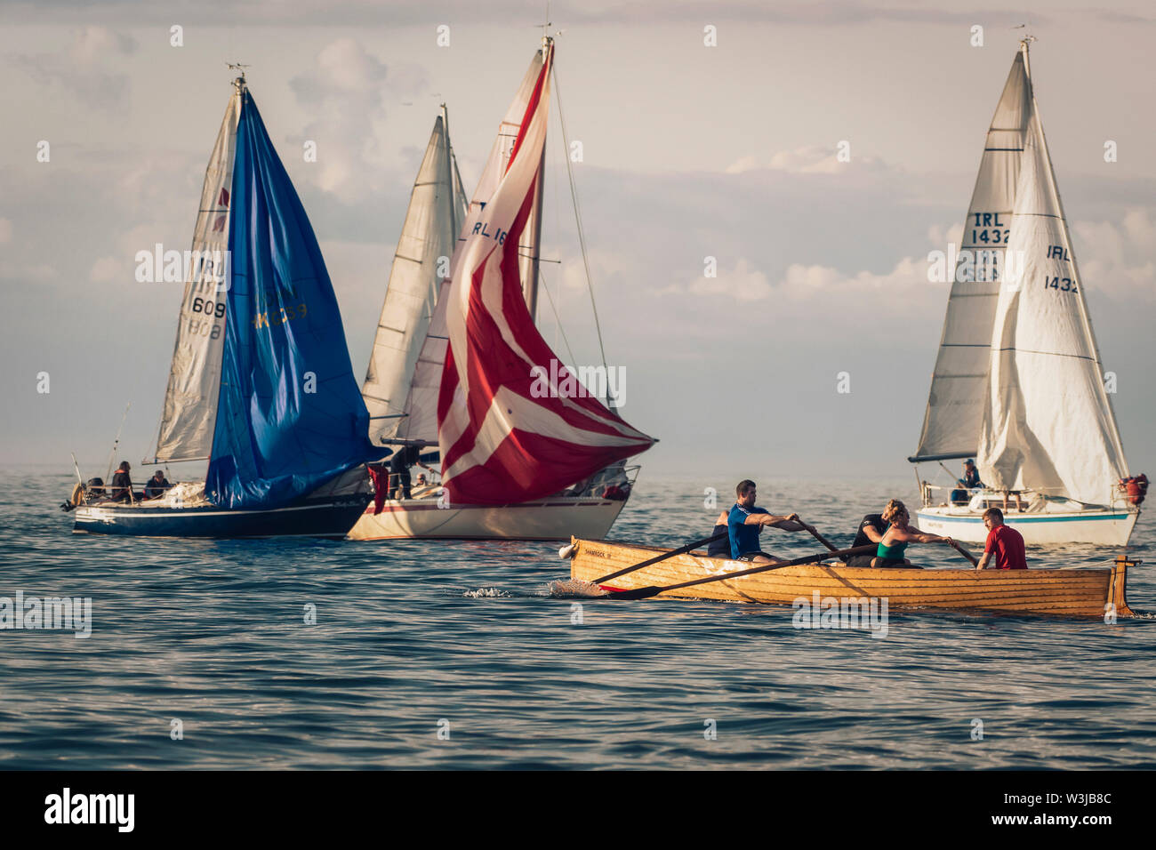 Sailing together. Rowing boat team training in front of group of