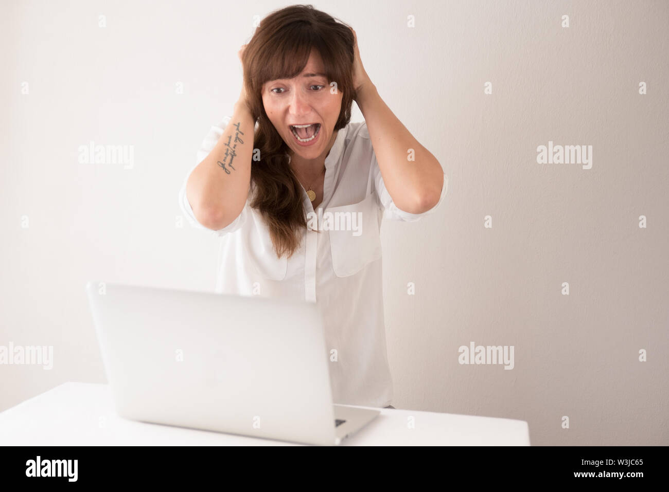 Young brunette woman having technical difficulties with her laptop computer in the office Stock Photo