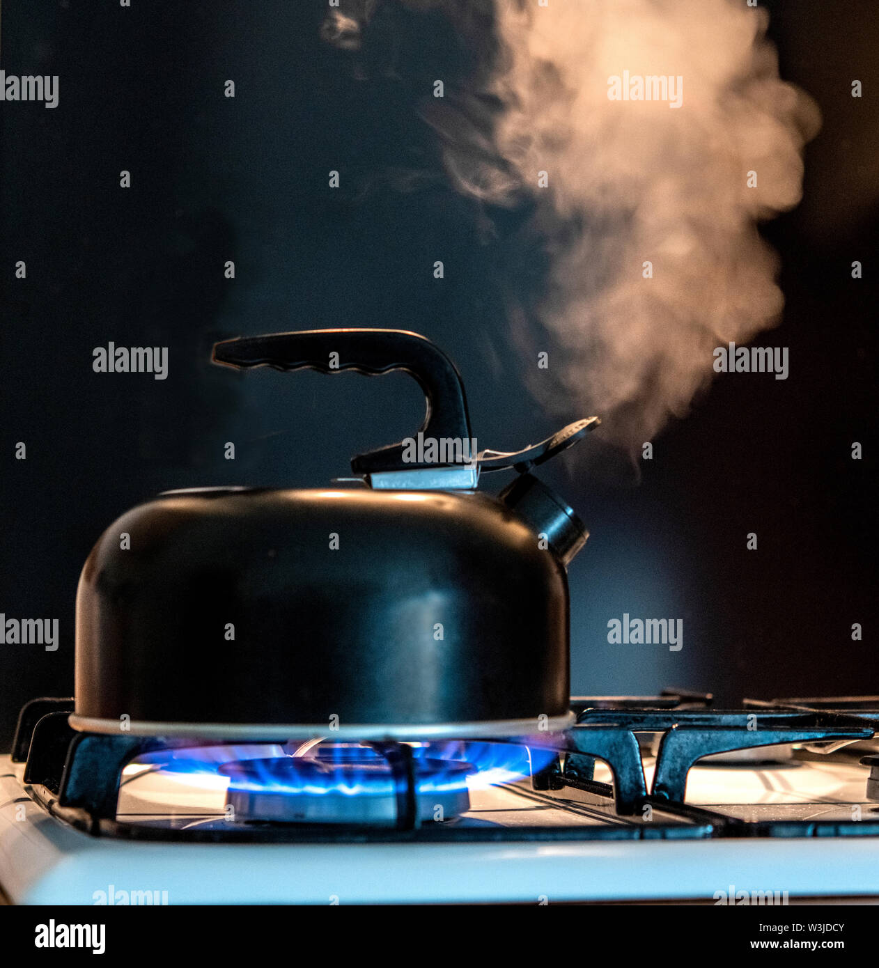 Kettle and steam on a gas hob ring Stock Photo Alamy