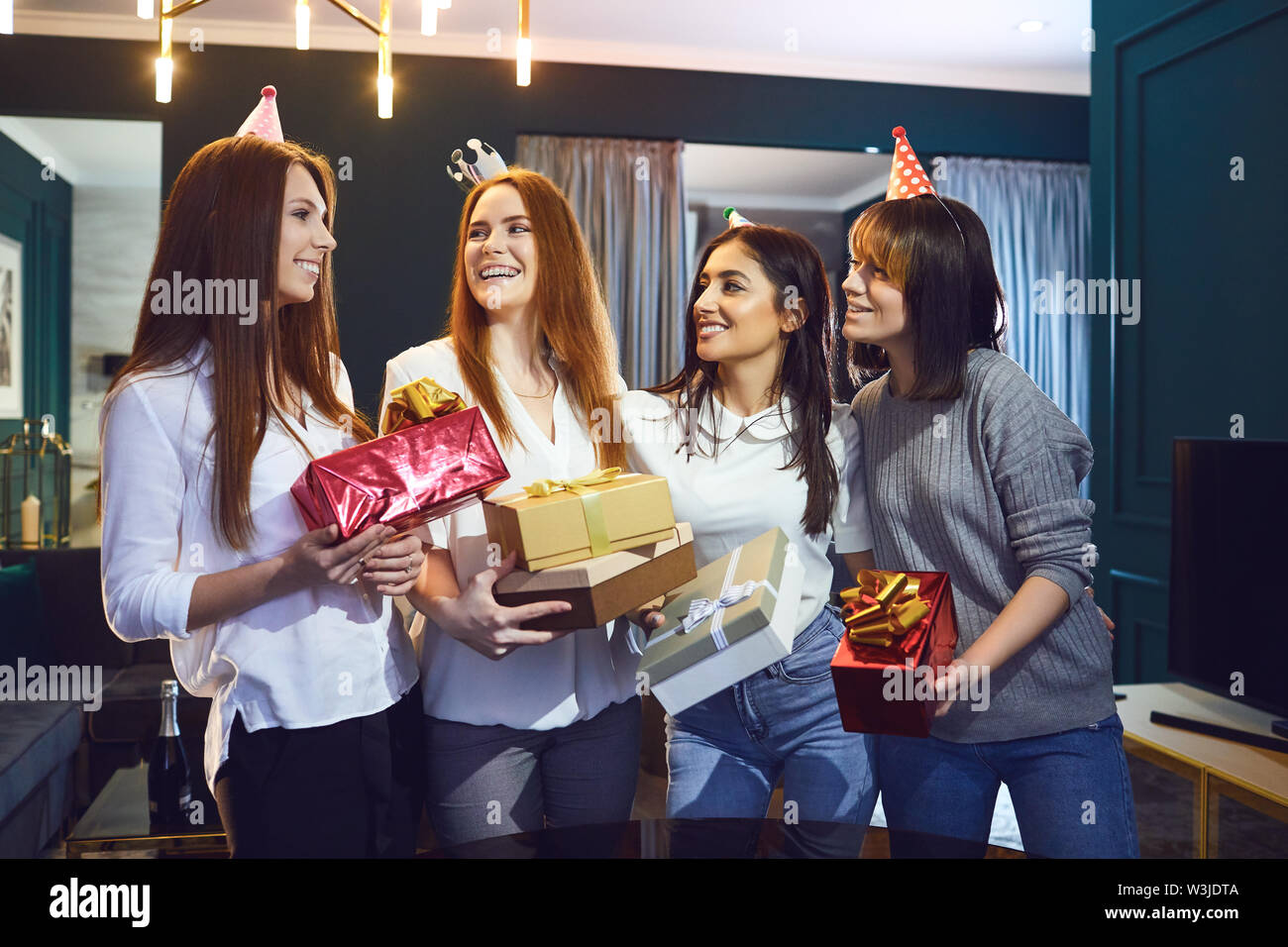 Group of cheerful beautiful women standing together with gifts while having birthday party Stock Photo