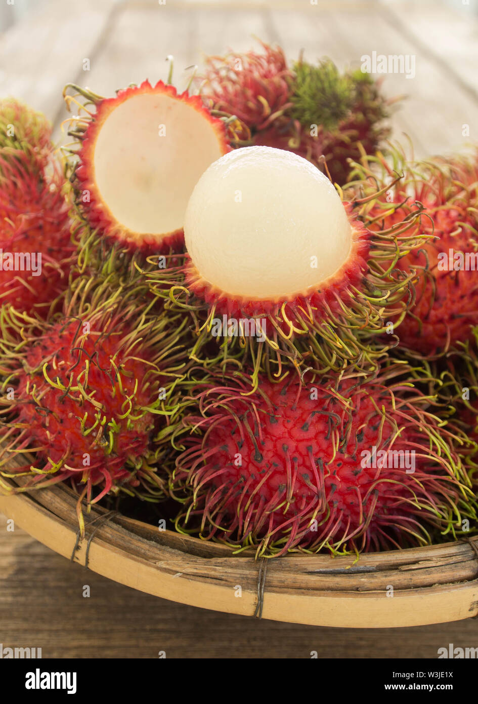 rambutan asian fruit in basket on wooden table. Stock Photo