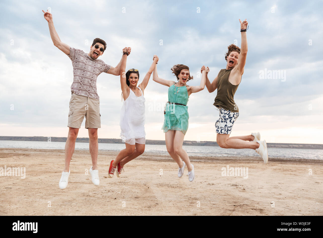 Group of a cheerful young friends jumping at the beach Stock Photo - Alamy