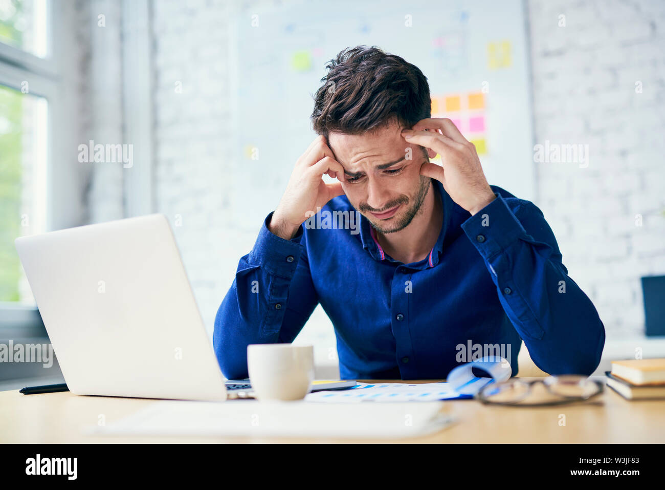 Stressed man in office looking on documents Stock Photo