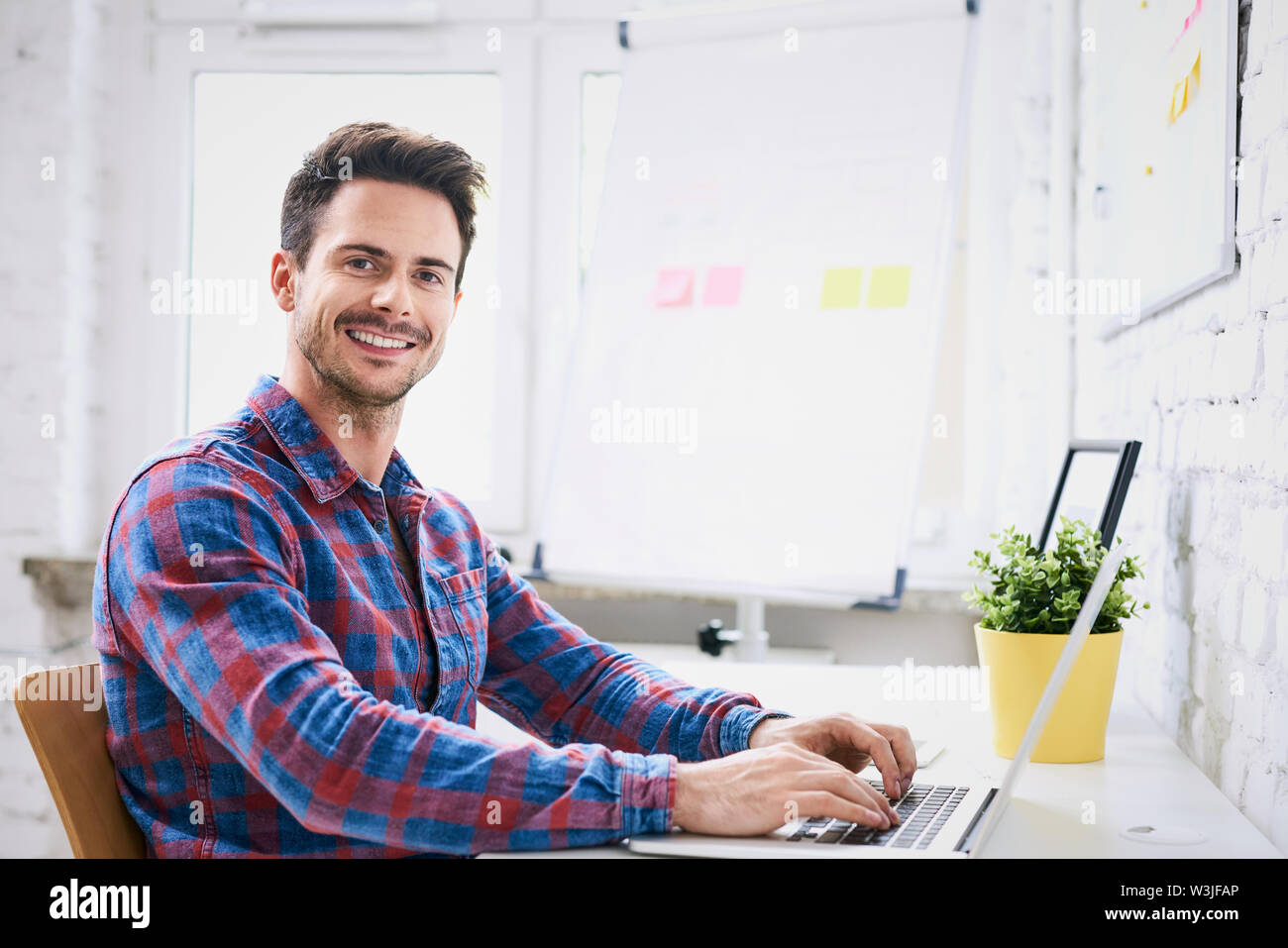 Succesful young web designer, programmer working on laptop in start-up office Stock Photo
