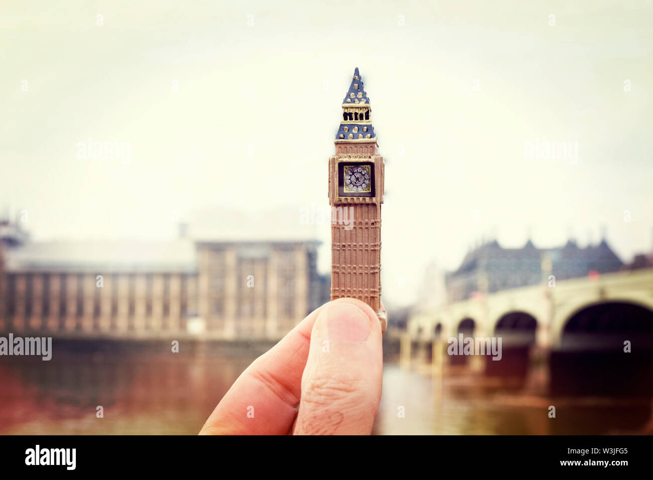 closeup of the hand of a man with a miniature of the Clock Tower in front of the real Clock Tower of the Palace of Westminster in London, United Kingd Stock Photo