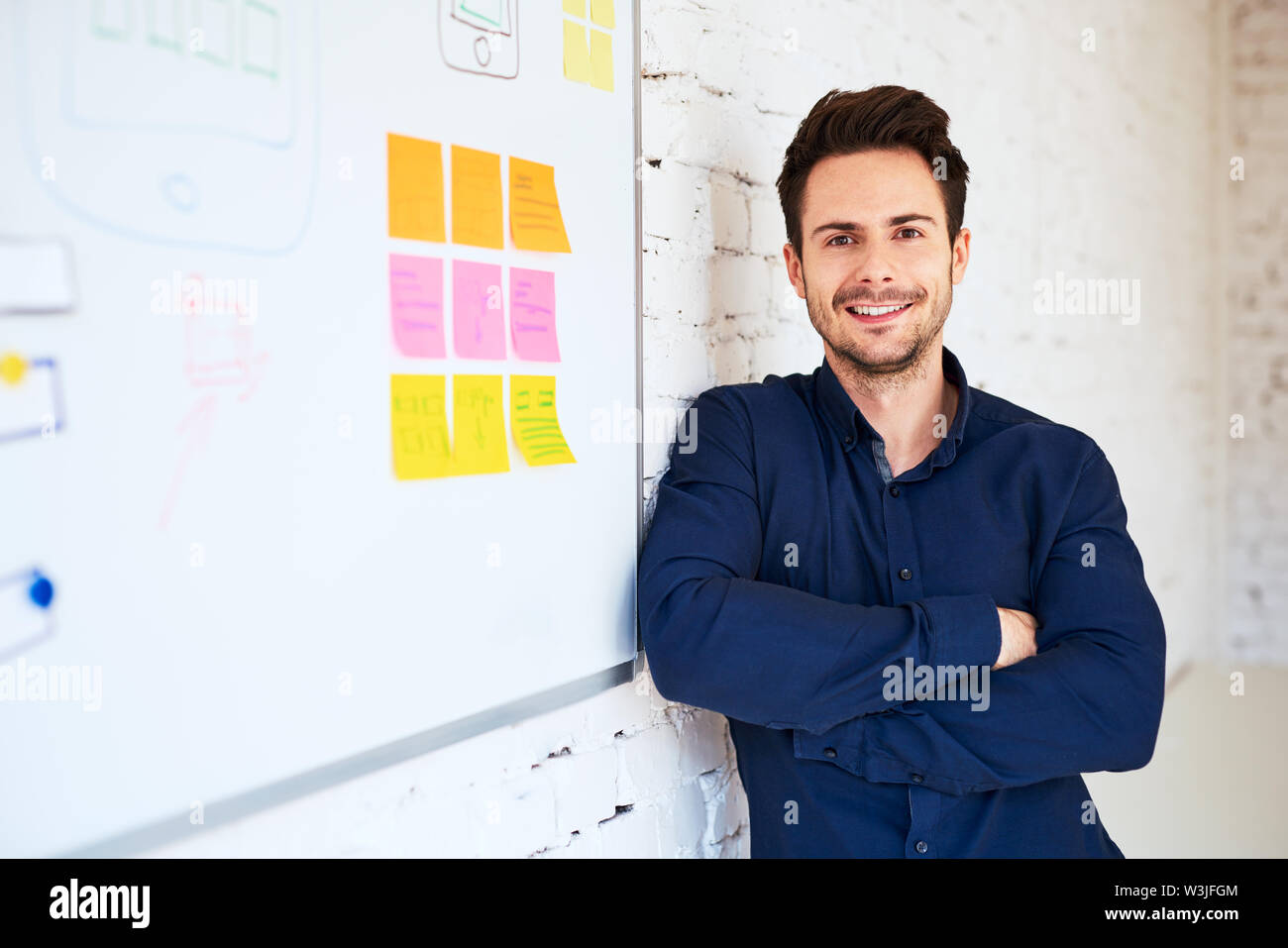 Happy young programmer, web designer standing at office Stock Photo