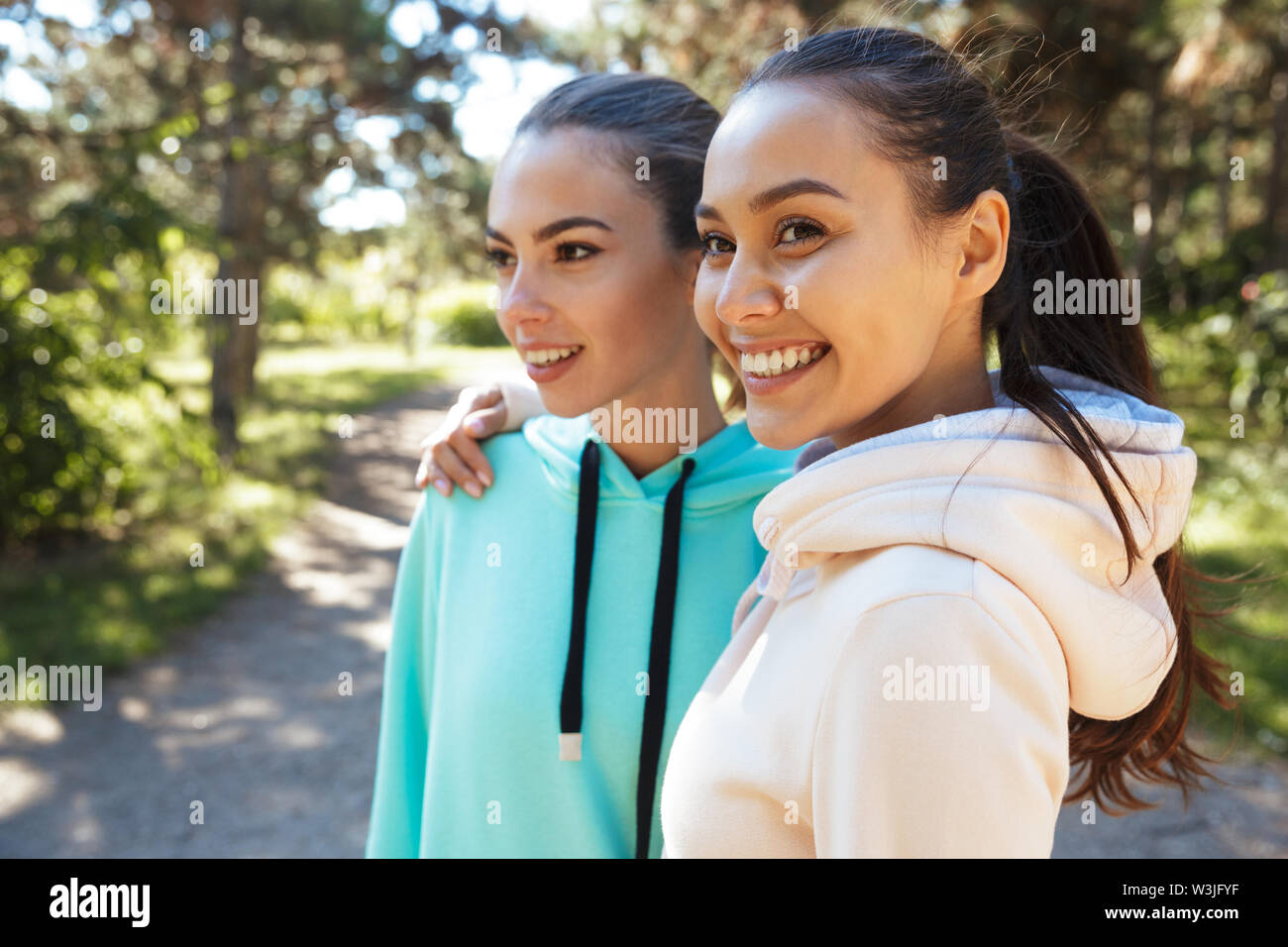 Attractive smiling fitness woman wearing hoodies working out at the