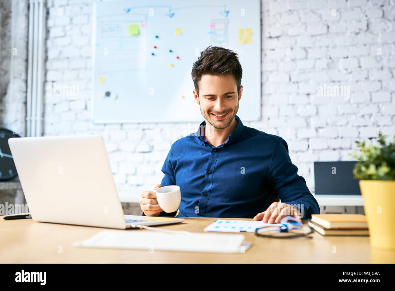 Young startup businessman drinking coffee and working using laptop and documents Stock Photo