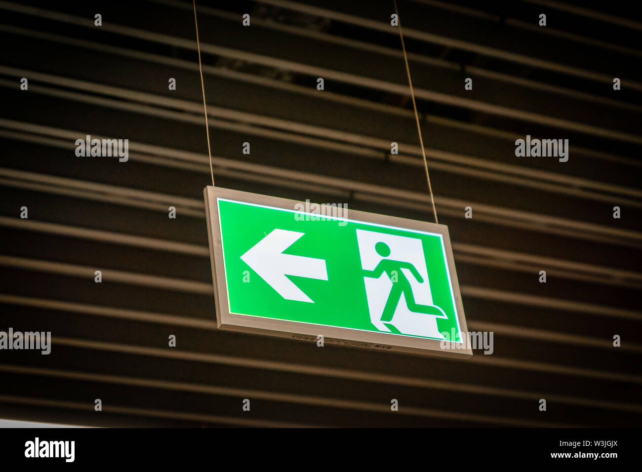 Emergency fire exit sign glowing green in the blacked out background at ...