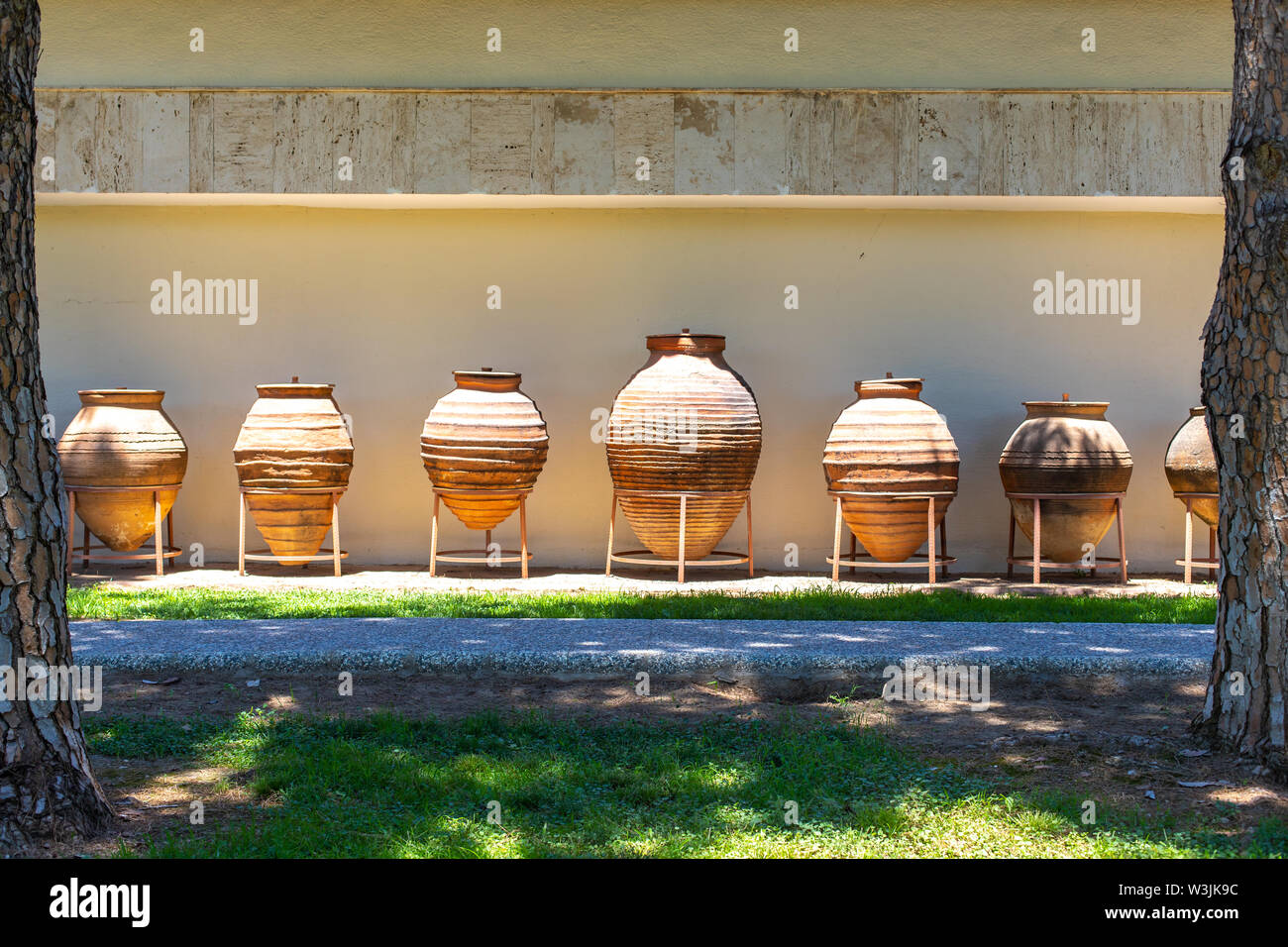 Huge earthenware jugs exhibited in the sun outside. Old pottery pots outside. Old orange clay jugs Stock Photo