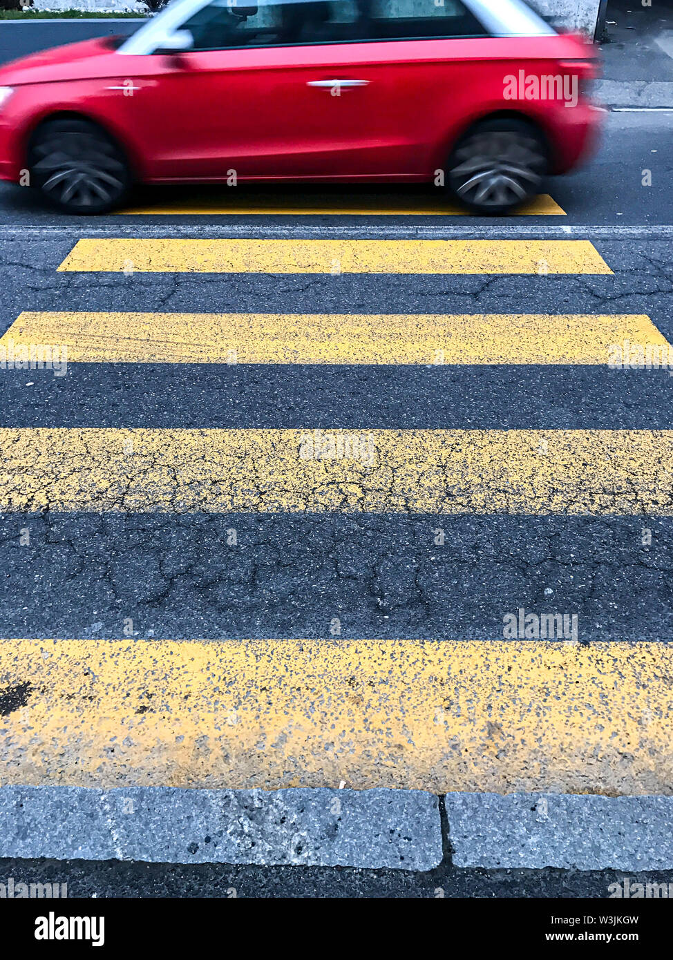 A red car passing over the pedestrian crossing Stock Photo
