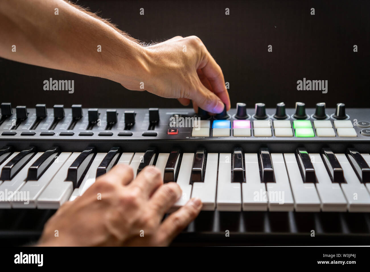 musician playing MIDI keyboard synthesizer piano keys closeup for
