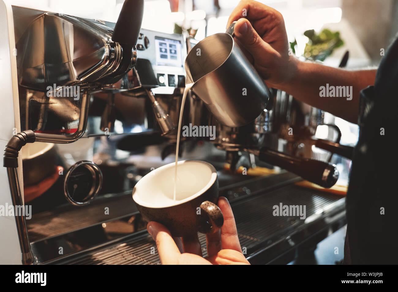 https://c8.alamy.com/comp/W3JPJB/barista-man-pouring-whipped-milk-from-frothing-pitcher-in-cup-with-coffee-standing-near-professional-coffee-machine-in-cafe-W3JPJB.jpg