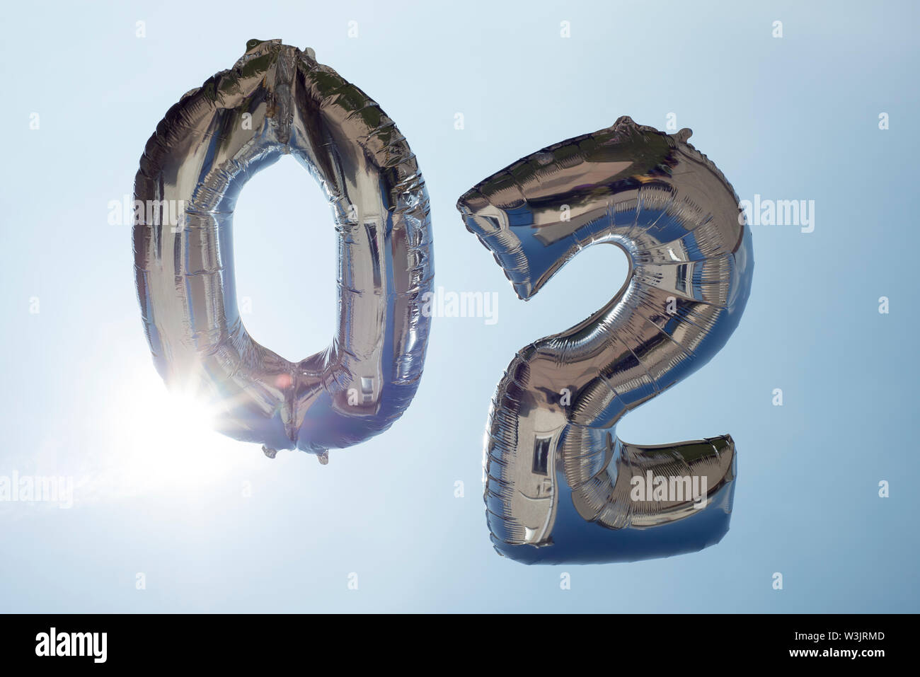 number 0 and 2 helium filled balloons against a blue sky Stock Photo