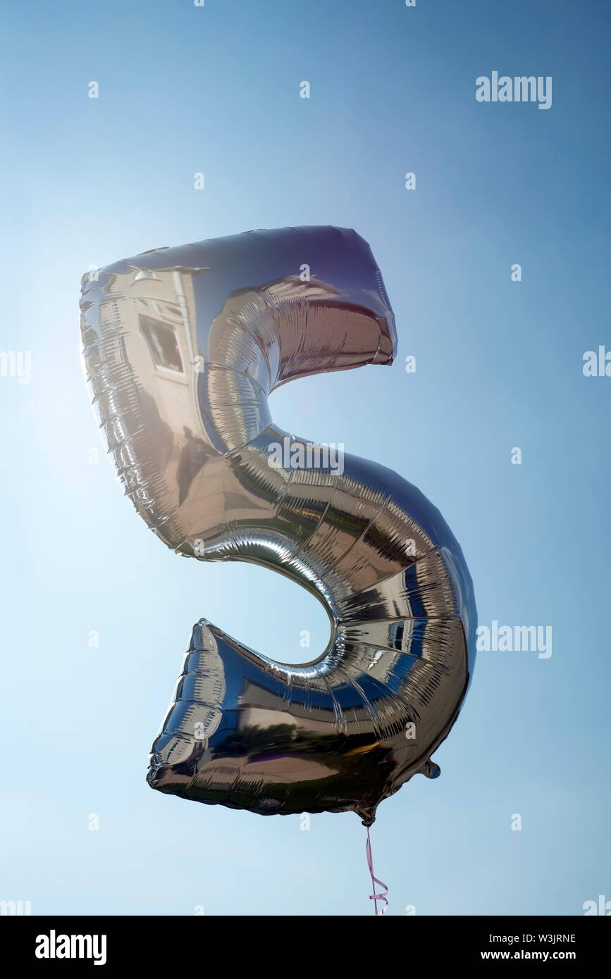 number 5 helium filled balloon against a blue sky Stock Photo