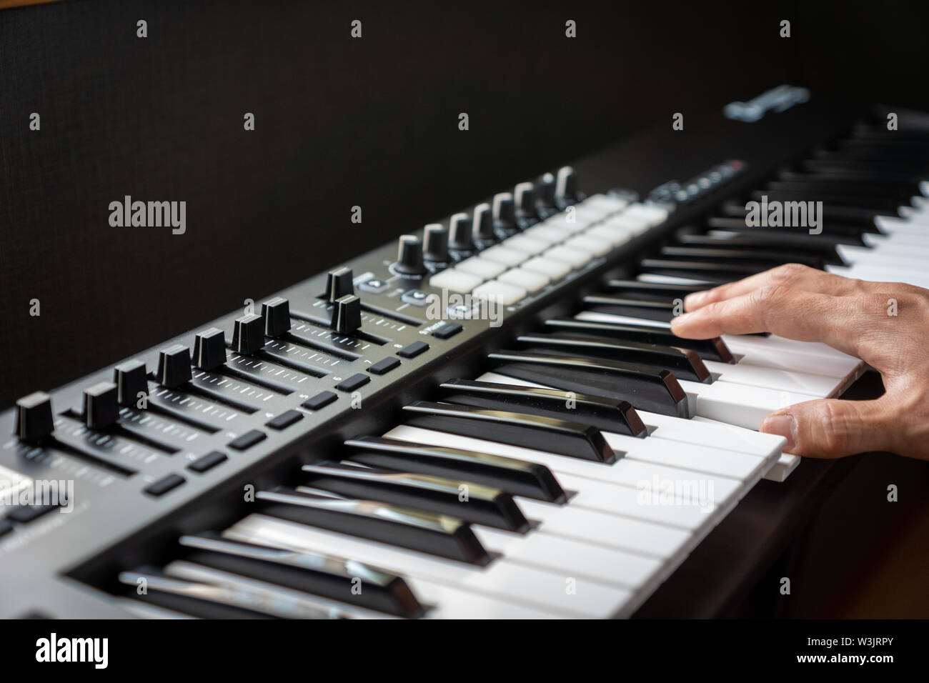 musician playing MIDI keyboard synthesizer piano keys closeup for