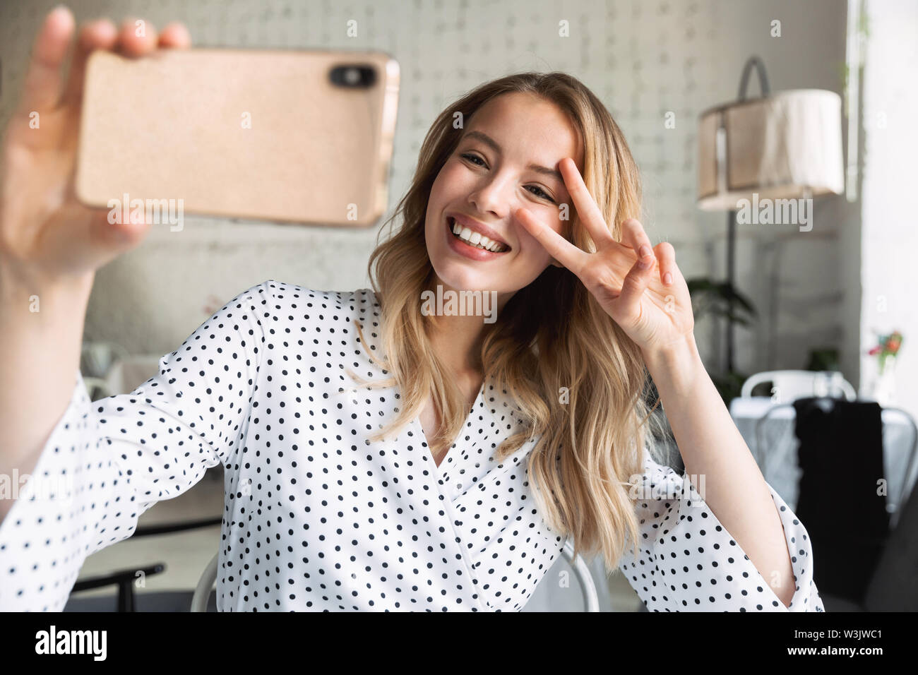 Beautiful young blonde woman sitting at the cafe indoors, taking a ...