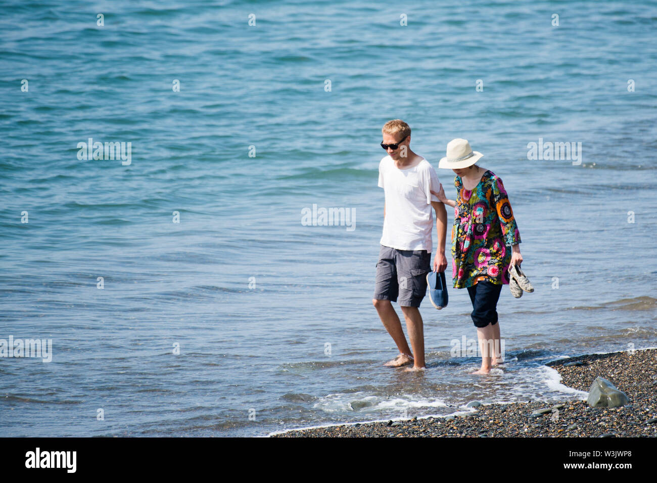 Aberystwyth Wales UK, Tuesday 16 July 2019 UK Weather: A couple walking in the shallow water at the seaside in Aberystwyth on a beautifully warm summers day in west Wales. photo Credit: keith morris/Alamy Live News Stock Photo