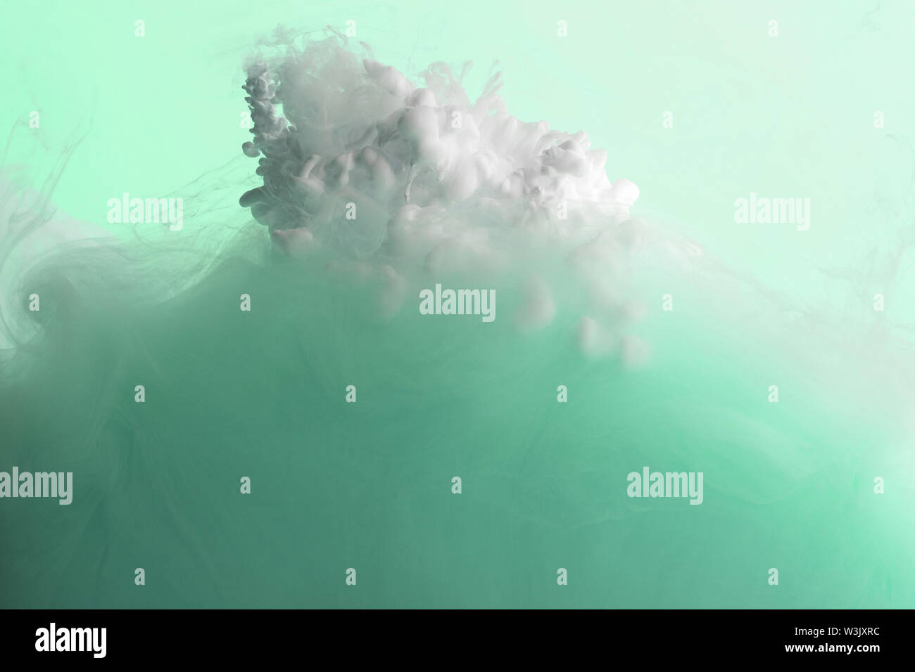 Close up view of green and white acrylic paint mixing in water Stock