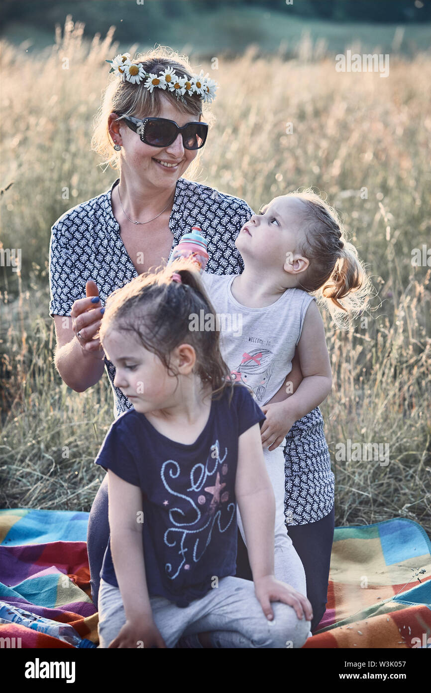 Family spending time together on a meadow, close to nature. Parents and children playing together, making coronet of wild flowers. Candid people, real Stock Photo