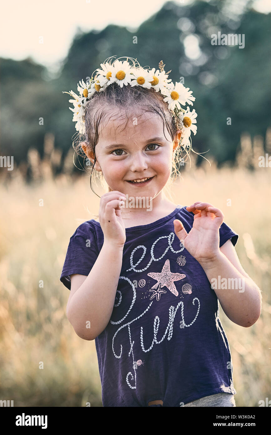 Little girl wearing a coronet of wild flowers on her head. Candid people, real moments, authentic situations Stock Photo