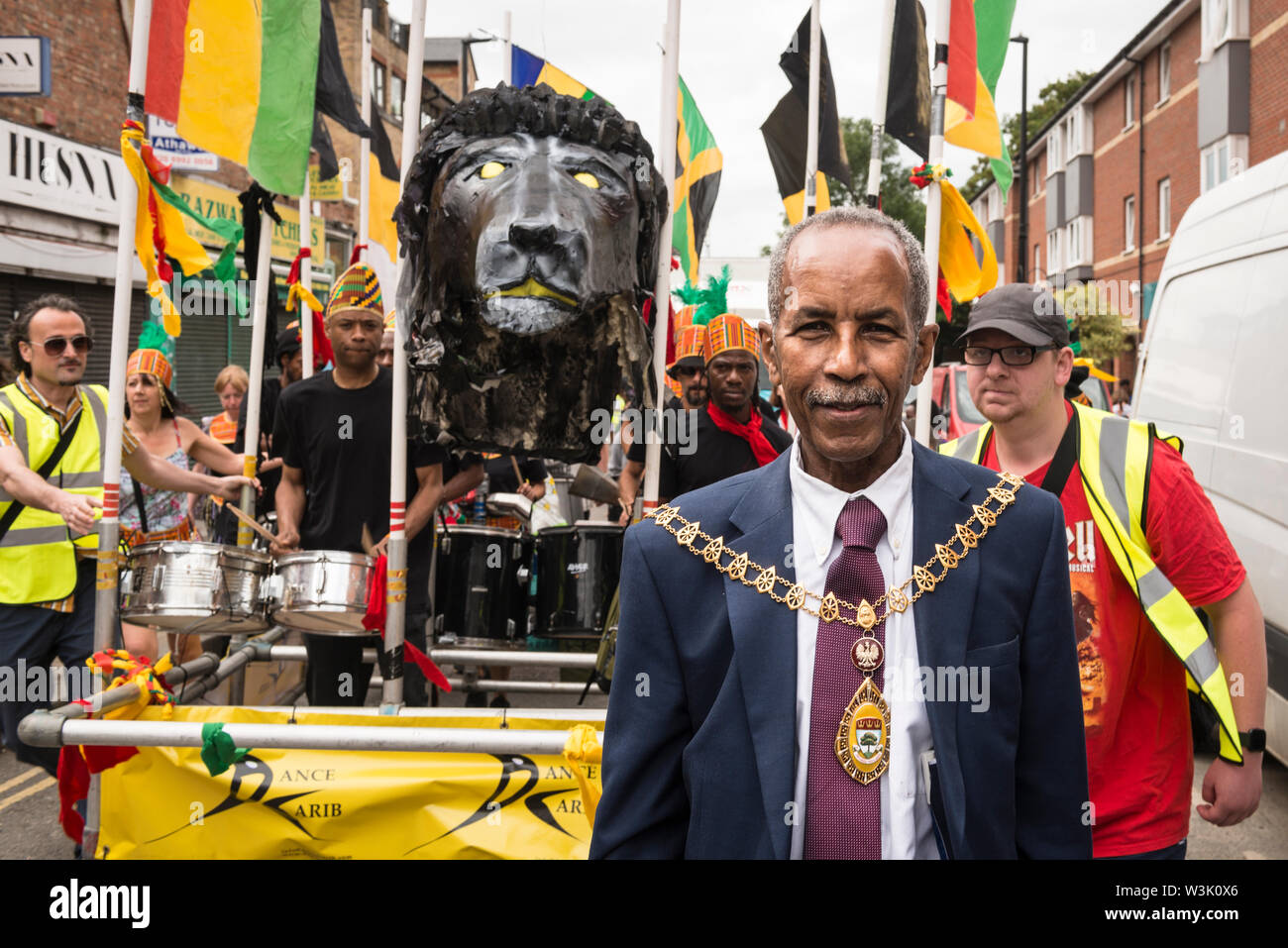 Councillor Dr. Abdullah Gulaid, Ealing's first Somali mayor ,and a Caribbean float at the start of Acton Carnival Parade, 2019. Acton London UK Stock Photo