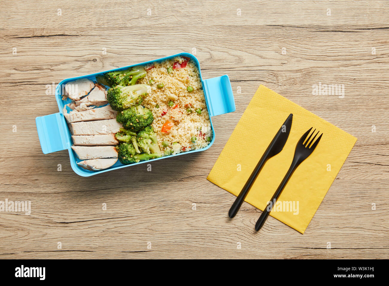 Top view of plastic lunch box with risotto, chicken and broccoli on