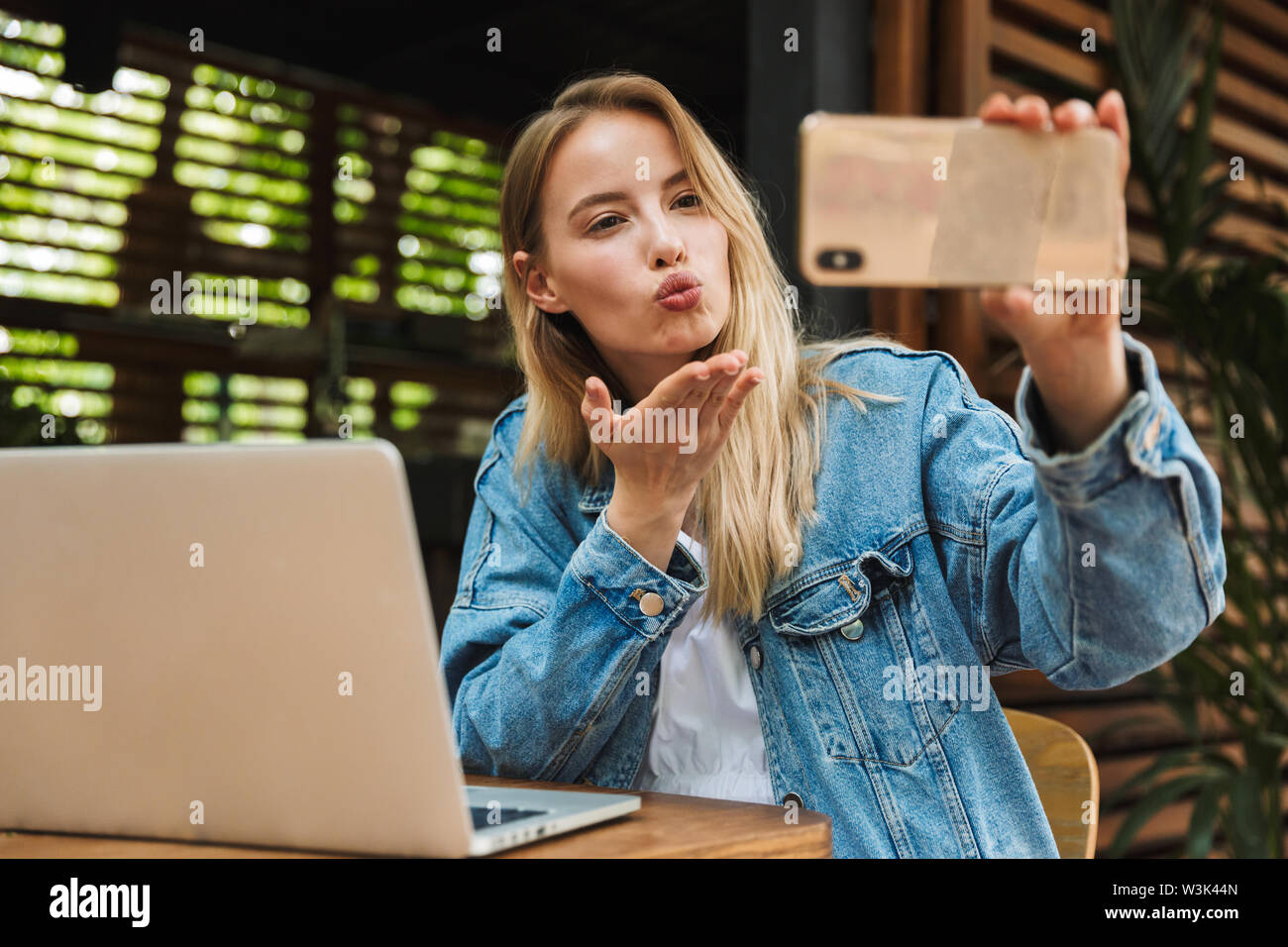 Image Of A Happy Young Pretty Blonde Woman In Cafe Using Laptop Computer And Mobile Phone Take A Selfie Blowing Kisses Stock Photo Alamy