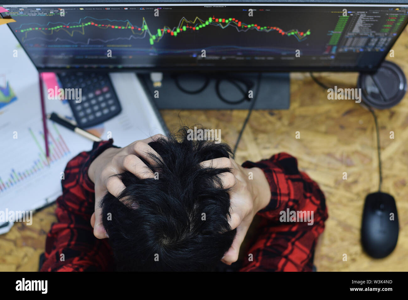 Fatigue man hands holding the head because of stress and having a headache at home office in while trading forex or stocks market online investment at Stock Photo