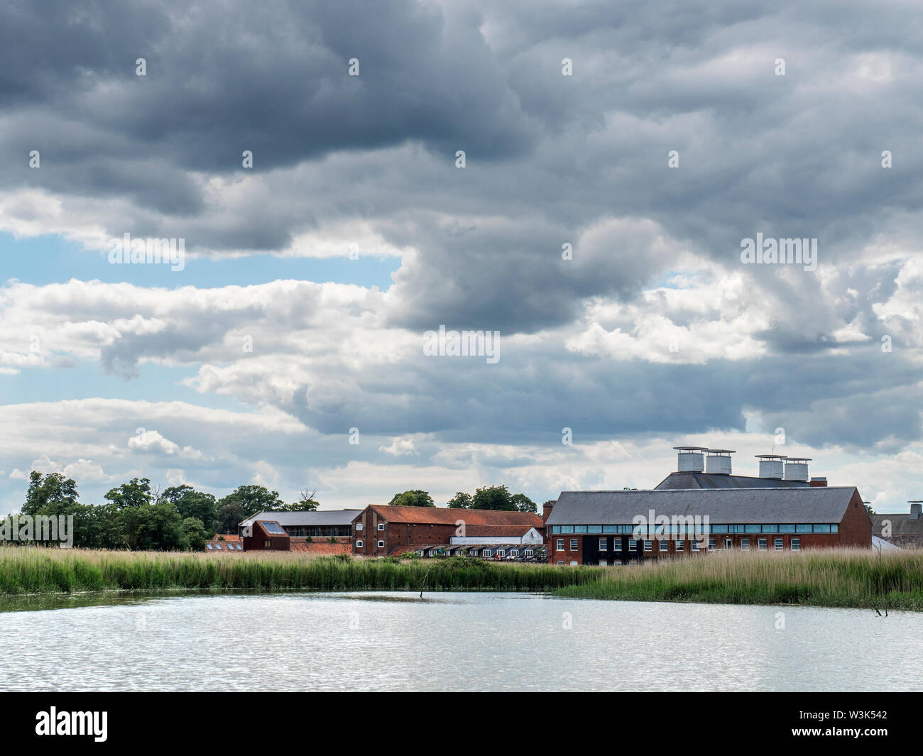 Summer storm clouds over Snape Maltings Concert Hall from the River Alde Snape Maltings Suffolk England Stock Photo