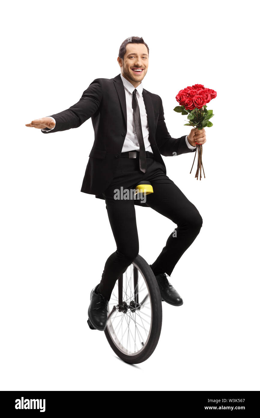 Full length portrait of a young businessman riding a unicycle and holding a bouquet of red roses isolated on white background Stock Photo