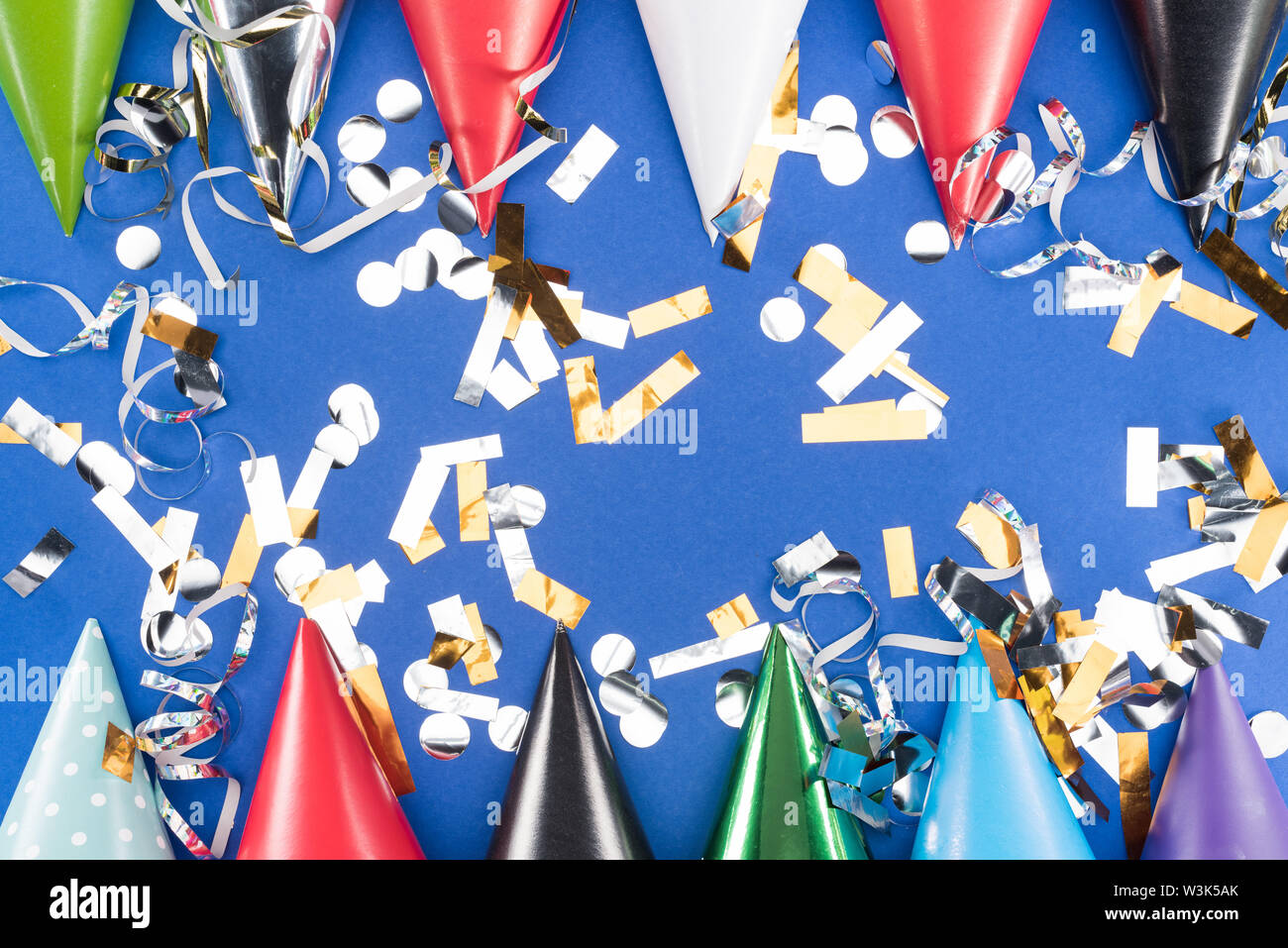 Colorful party hats and silver confetti on blue background Stock Photo ...