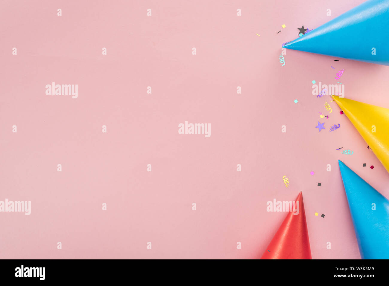 Top view of party hats and confetti on pink background Stock Photo - Alamy