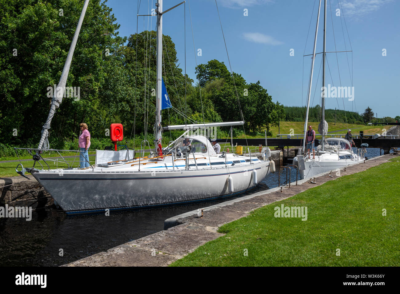 Two yachts manoeuvre into position within lock 10 before water level is lowered – Dunardry on Crinan Canal, Argyll and Bute, Scotland, UK Stock Photo